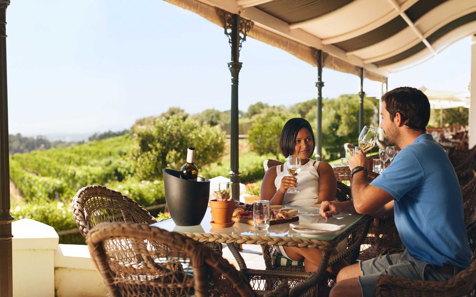 Couple tasting wine on a terrace overlooking Napa Valley vineyards